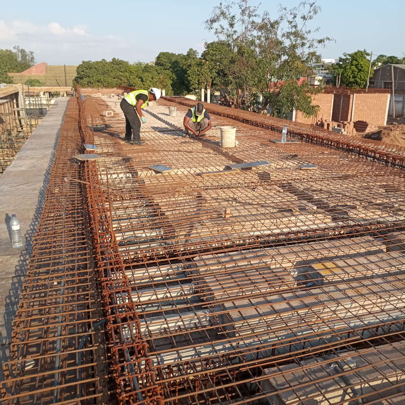 Estrutura armada em desenvolvimento, com equipa a trabalhar sobre a cofragem