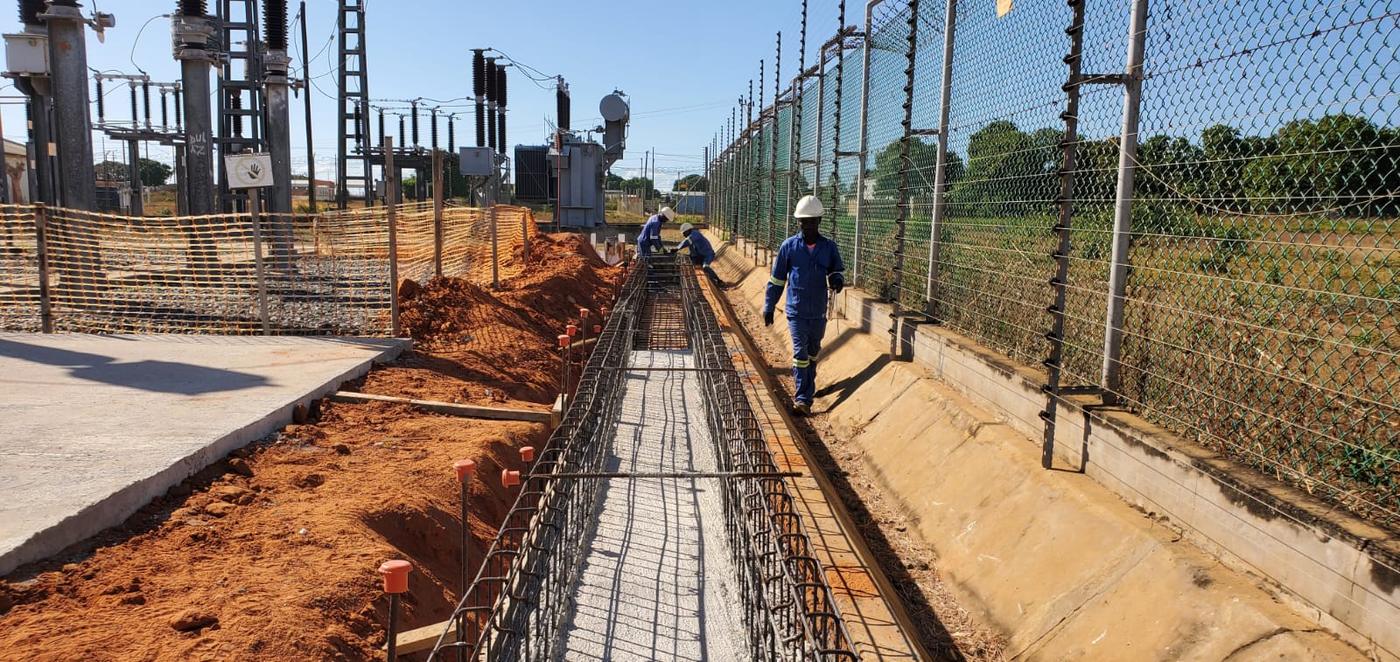 Vala betonada ao longo de uma vedação, com trabalhador ao fundo